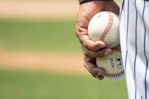 A person holding two baseballs in one hand