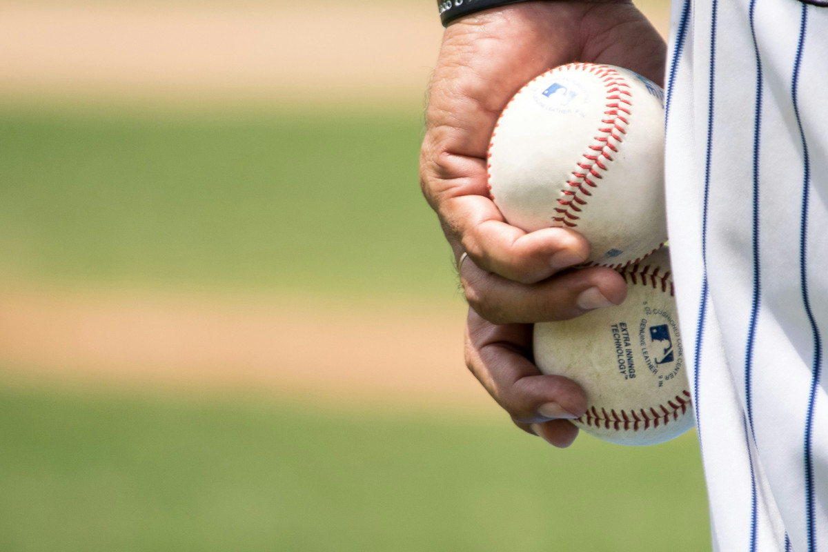 A person holding two baseballs in one hand
