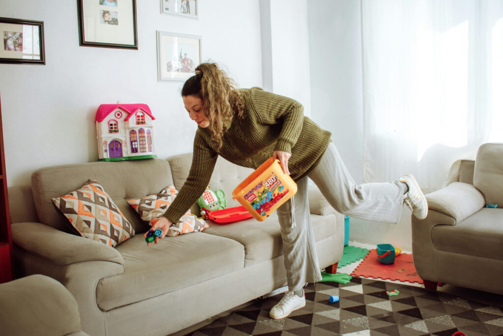 A woman cleaning toys in the living room